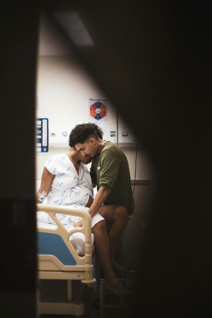 A couple embraces in a hospital room, conveying love and support during a challenging time.